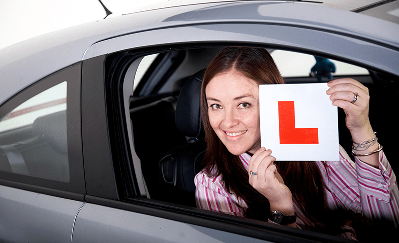 GIRL IN CAR HOLDING L PLATE